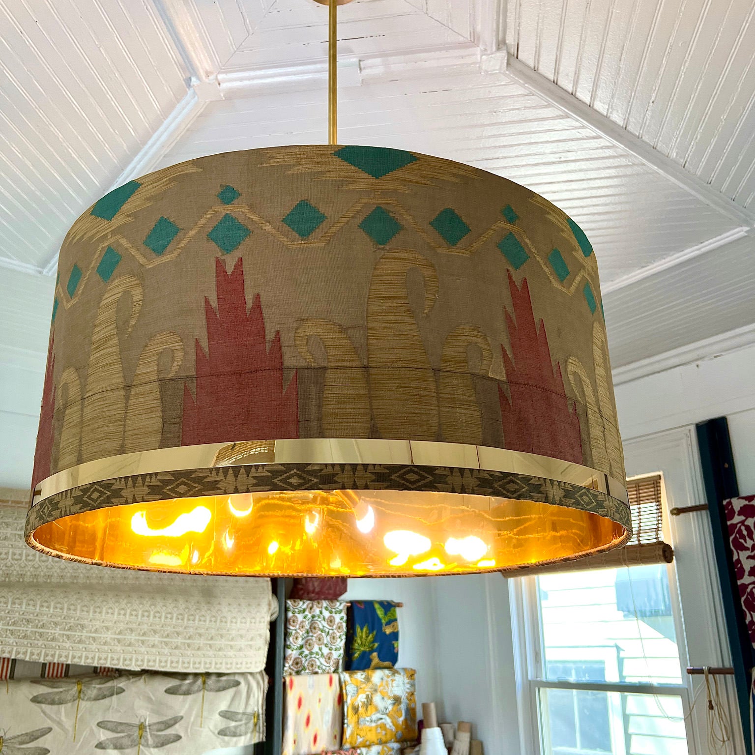 blue, orange and light brown drum shade with fabric hanging on wall
