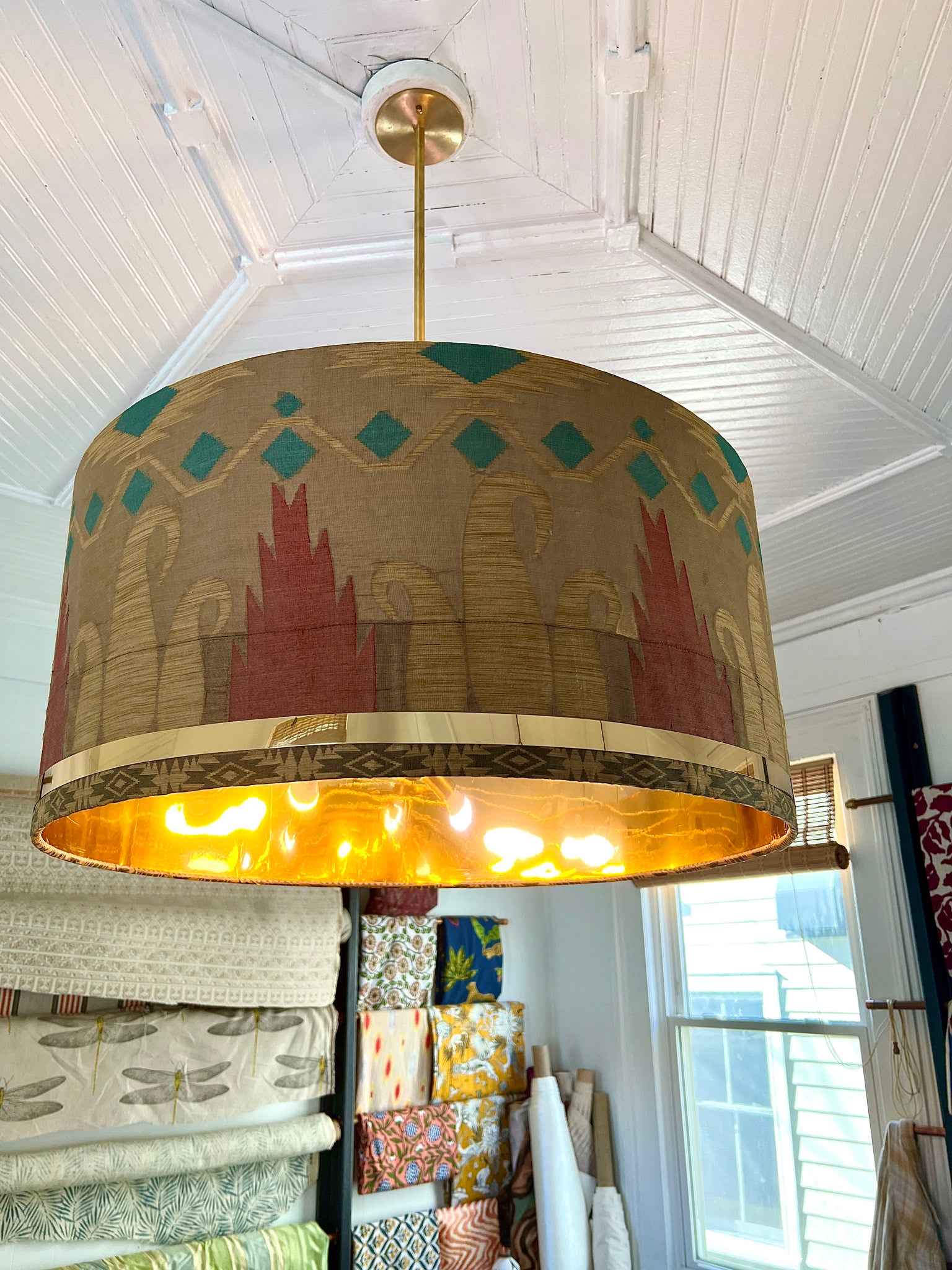 blue, orange and light brown drum shade with fabric hanging on wall