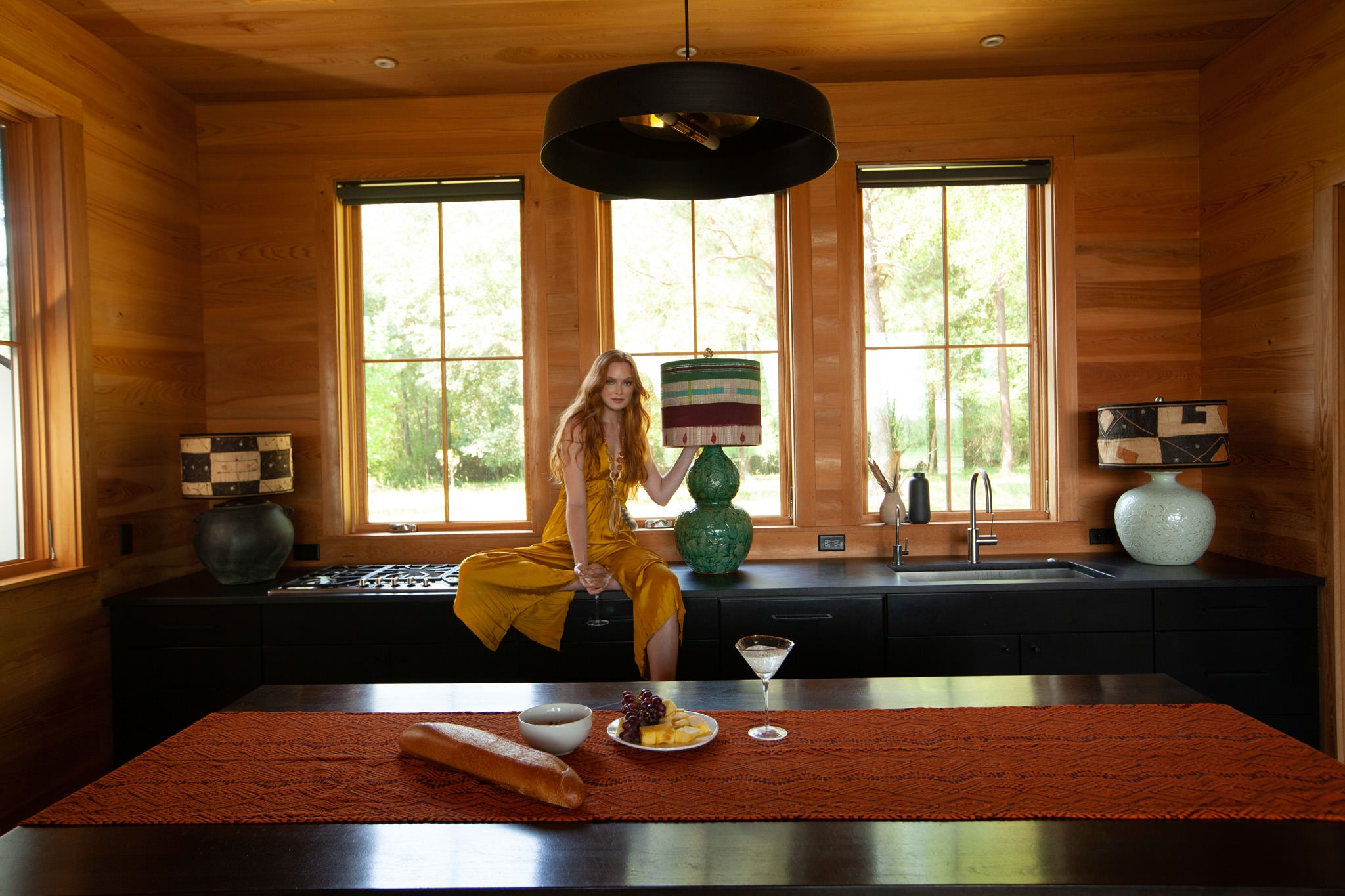 beautiful girl with red hair sitting on a cabinet turning on a lamp